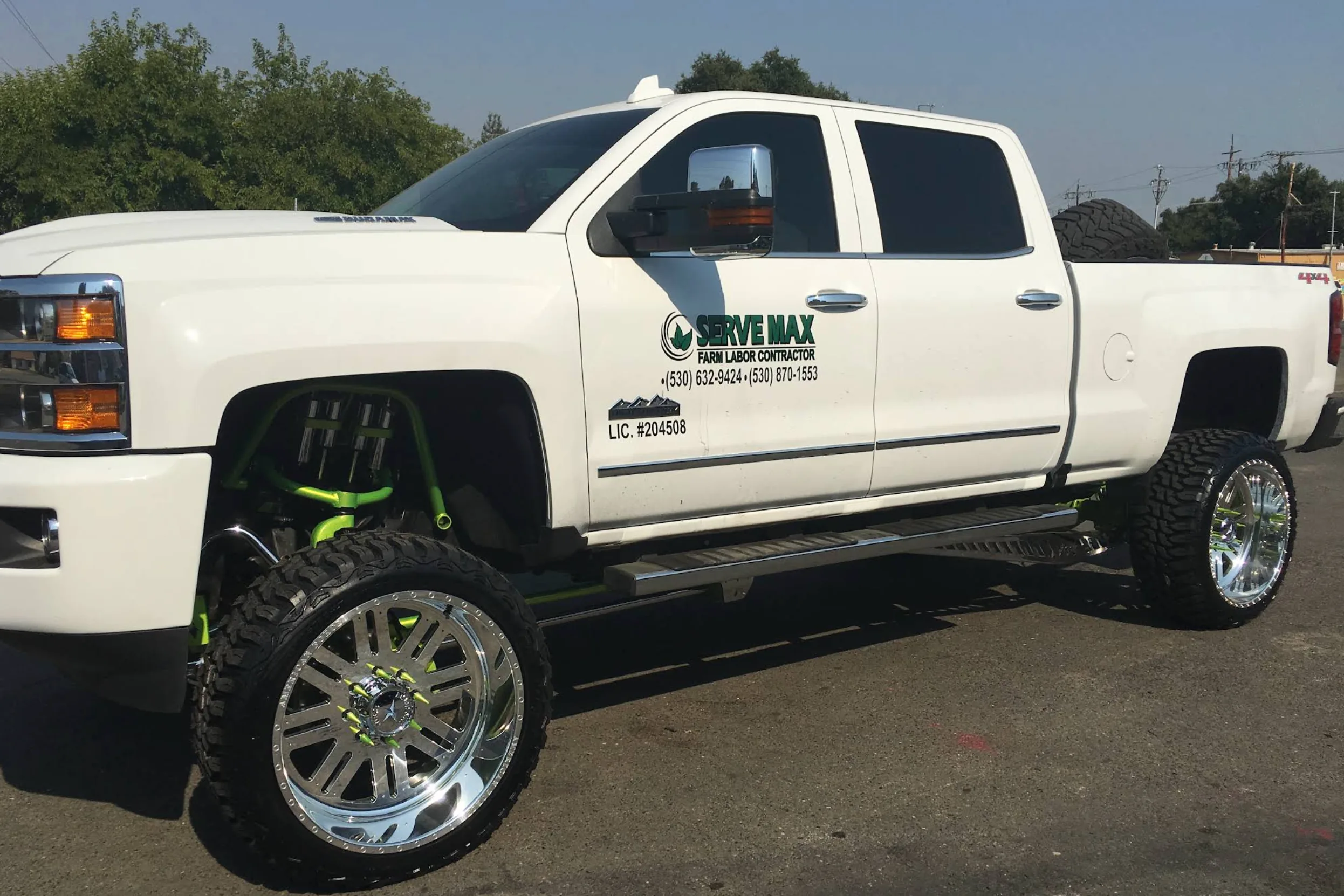 Lifted white Silverado on polished custom wheels and mud-terrain tires