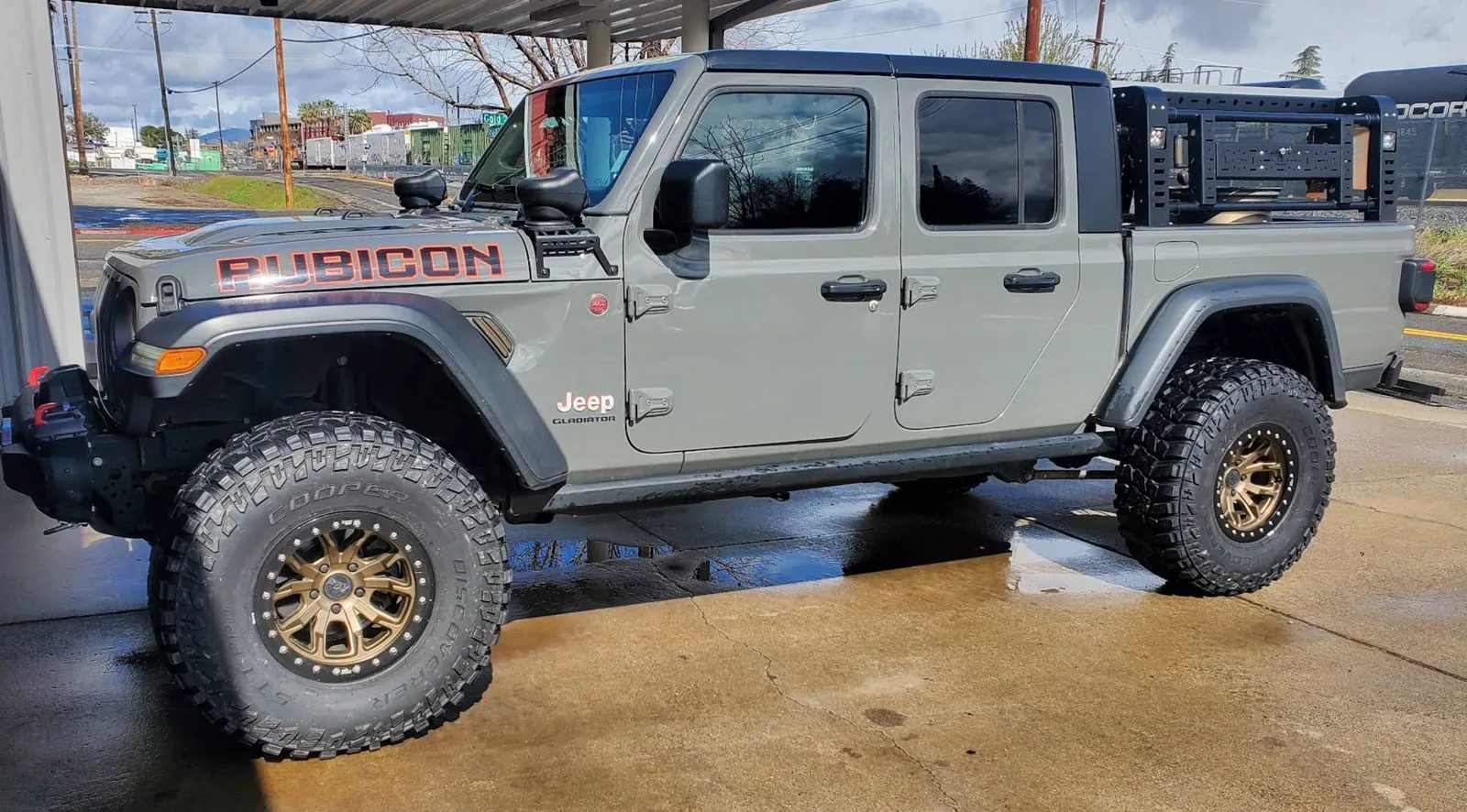 Lifted gray Jeep Gladiator Rubicon on bronze beadlock-style wheels and mud-terrain tires