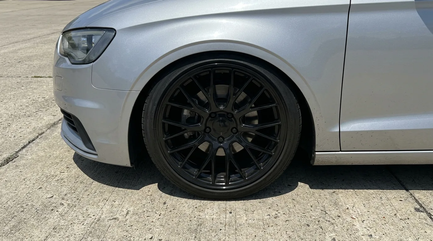 Lowered silver car with a gloss black multi-spoke wheel tucked under the fender