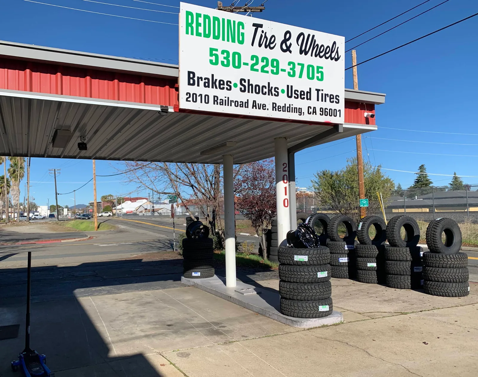 New all-terrain and mud-terrain tires and black wheels on display under the Redding Tires and Wheels sign